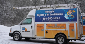 Holtzople heating & air conditioning vans sitting in the snow on a winter day