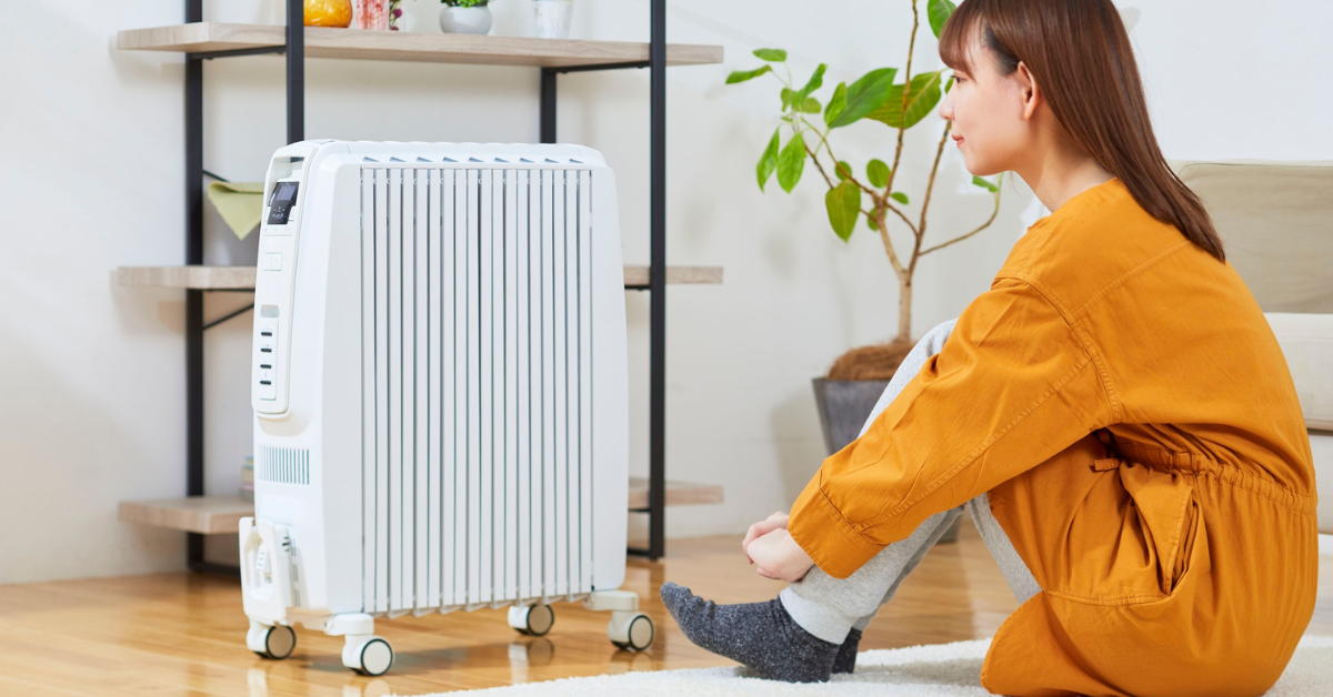 A mid-twenties woman sitting by a space heater
