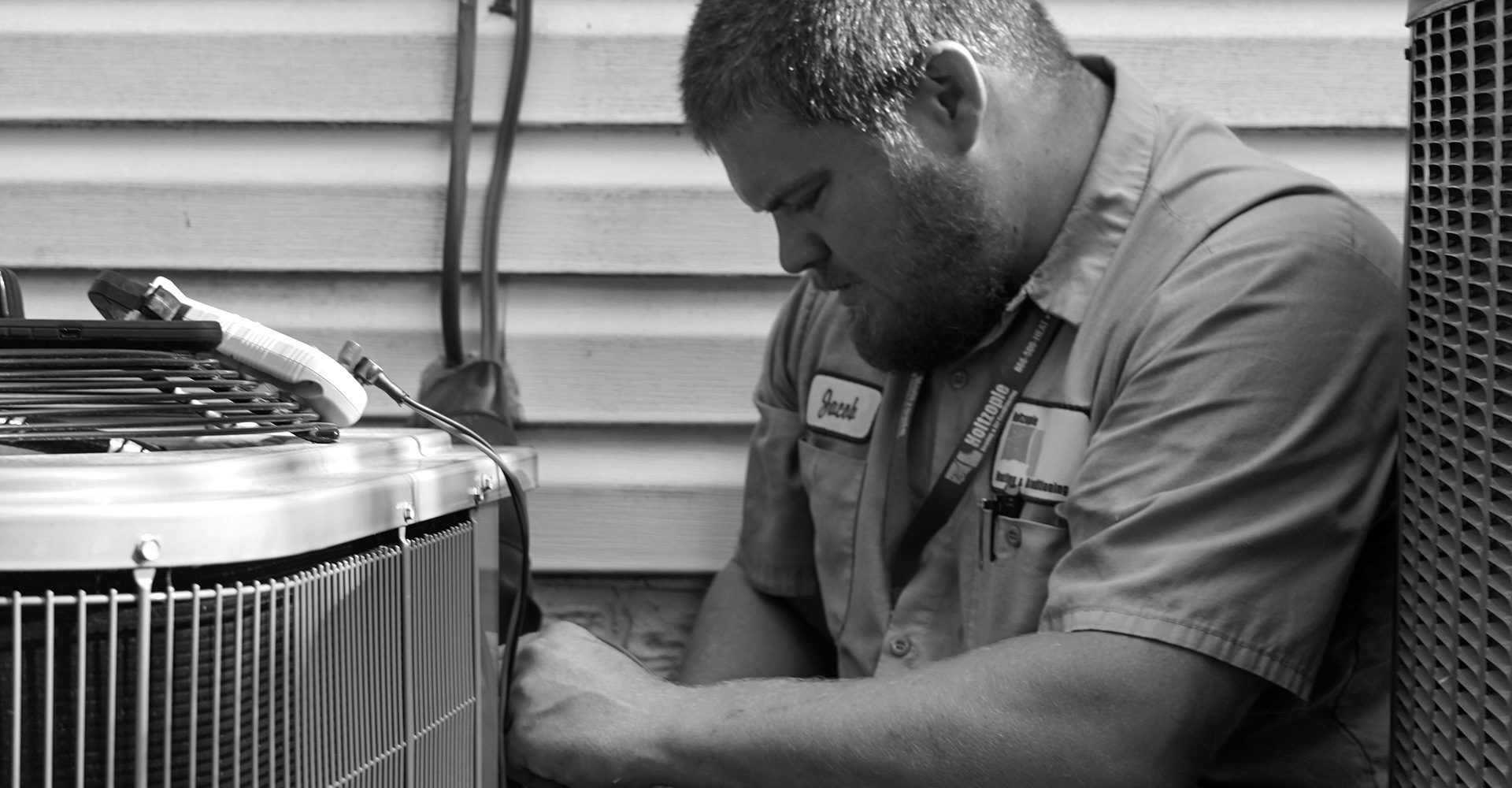 Holtzople technician servicing an outdoor air conditioning condenser